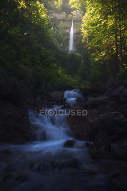 Paisaje de poderosa cascada y río que fluye en bosques en las tierras altas de Eslovenia en larga exposición - foto de stock