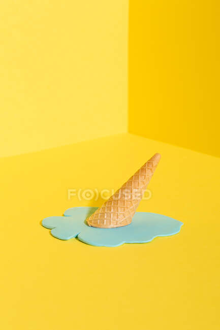 Мокап синий таяние мороженого в вафельном конусе помещен на желтый фон, представляющий летнюю концепцию — стоковое фото