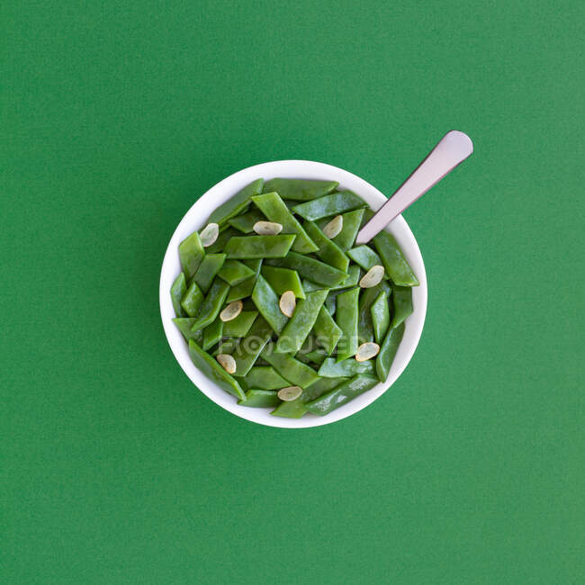 De arriba de la ensalada sana con los frijoles verdes y los trozos del ajo en la escudilla servida a la mesa verde - foto de stock