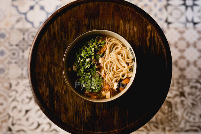 De cima tigela de cerâmica com refeição ramen chinês na bandeja de madeira círculo no fundo ornamento oriental — Fotografia de Stock