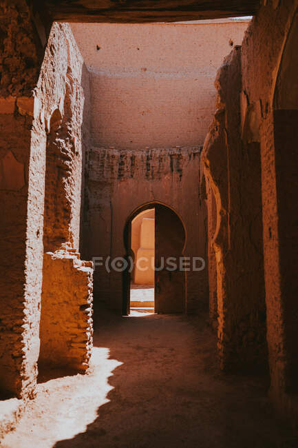 Fassade eines schäbigen islamischen Bogengebäudes mit offener Tür an einem sonnigen Tag auf der Straße von Marrakesch, Marokko — Stockfoto