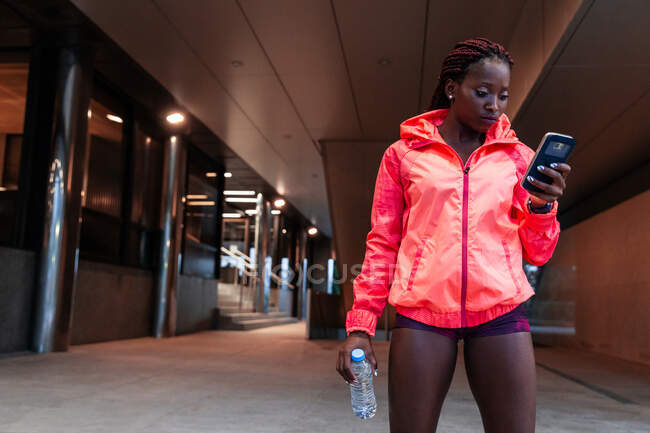 Sportswoman utilisant un smartphone dans la rue — Photo de stock