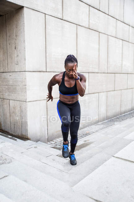 Starke Afroamerikanerin läuft Treppe hinauf, während sie in der Nähe eines modernen Gebäudes an der Stadtstraße trainiert — Stockfoto