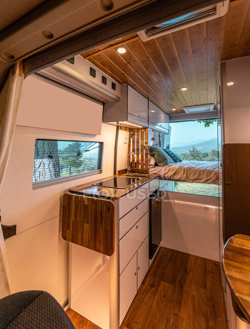 Moderno interior de cocina y dormitorio en furgoneta estacionado en el prado en la naturaleza - foto de stock
