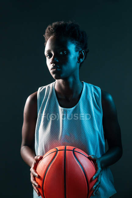 Чорна жінка з баскетбольним вбранням в студії з використанням кольорових гелів і проекторних вогнів — стокове фото