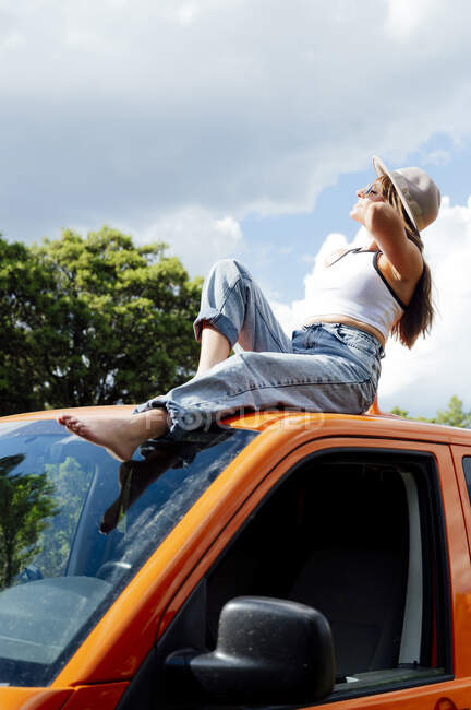 Heitere Forscherin sitzt auf dem Dach des Transporters und genießt das Sommerabenteuer an einem sonnigen Tag — Stockfoto