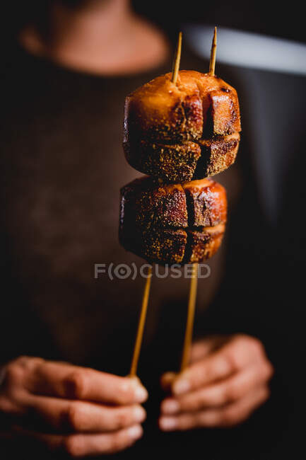 Woman holding in both hands roasted Chinese bread on wooden skewers — Stock Photo