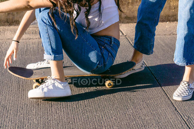 Ernte bis zur Unkenntlichkeit weibliche Geschwister in lässigem Outfit Skateboard fahren auf Gehweg, während die Ausgaben Wochenende auf sonnigem Tag — Stockfoto