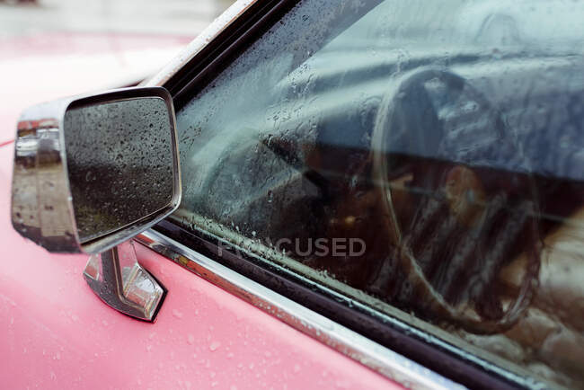 Detalhe de um espelho retrovisor de um carro rosa clássico em um dia chuvoso — Fotografia de Stock