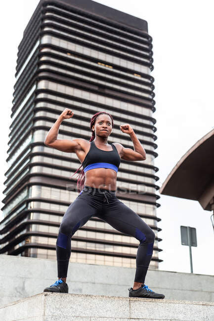 Атлетическая афроамериканская спортсменка позирует перед современным бетонным зданием в городе — стоковое фото