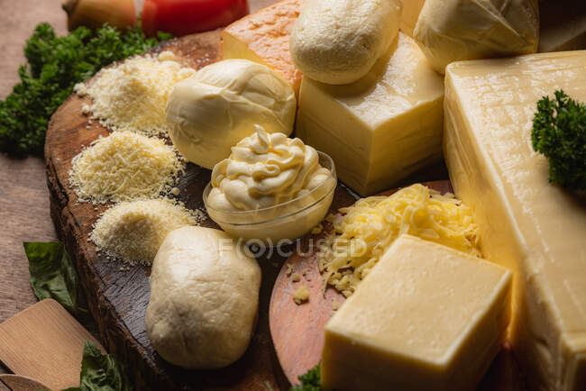 Coleção de queijo italiano na mesa com legumes frescos e salsa encaracolada com folhas de manjericão em espátulas — Fotografia de Stock