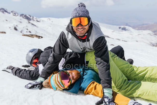 Anonymous cheerful male athletes in sportswear and goggles having fun on snowy ridge in sunlight in Spain — Stock Photo