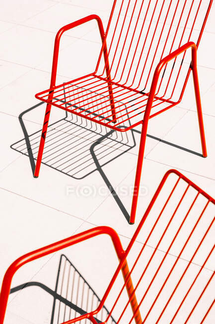 Sommer im Freien rote Metallstühle auf weißem Boden im Sonnenlicht mit Schatten platziert — Stockfoto