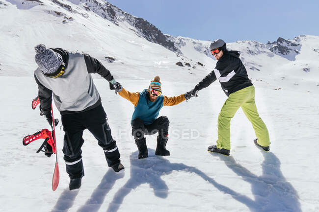 Anonymous male athletes in sportswear pulling partner by hands against Sierra Nevada in province of Granada Spain — Stock Photo
