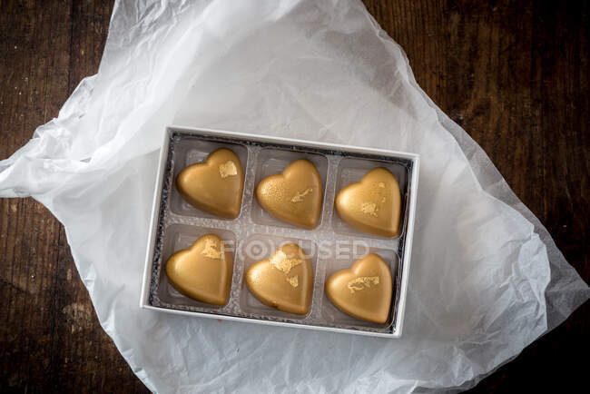 Вид сверху сладких разноцветных шоколадных конфет в коробке, установленной на деревянном столе — стоковое фото