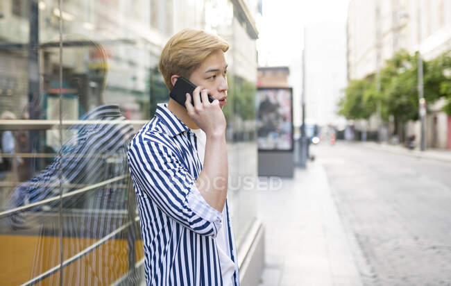 Азиатский мужчина разговаривает с сотовым на городской улице — стоковое фото