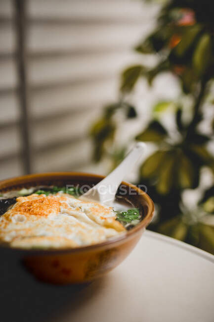 Yummy Asian soup with noodles and fried egg on terrace — Stock Photo