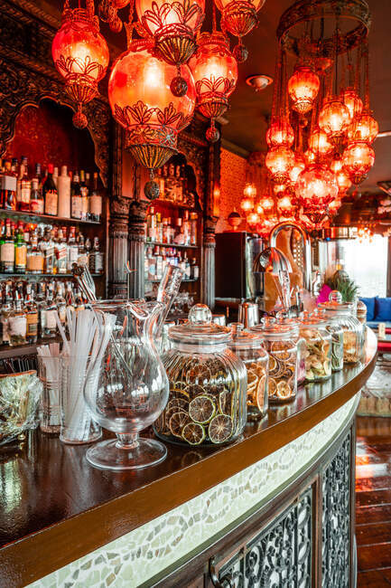 Interno di accogliente pub con lampade illuminate e bancone in legno con decorazioni assortite — Foto stock