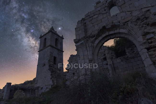 De baixo de restos arruinados de castelo de pedra antiga com torre sob céu estrelado noite com Via Láctea — Fotografia de Stock