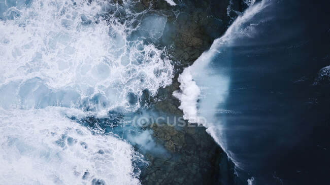 Vue de drone de paysages à couper le souffle de vagues de mer mousseuses s'écrasant sur le rivage rocheux rugueux — Photo de stock