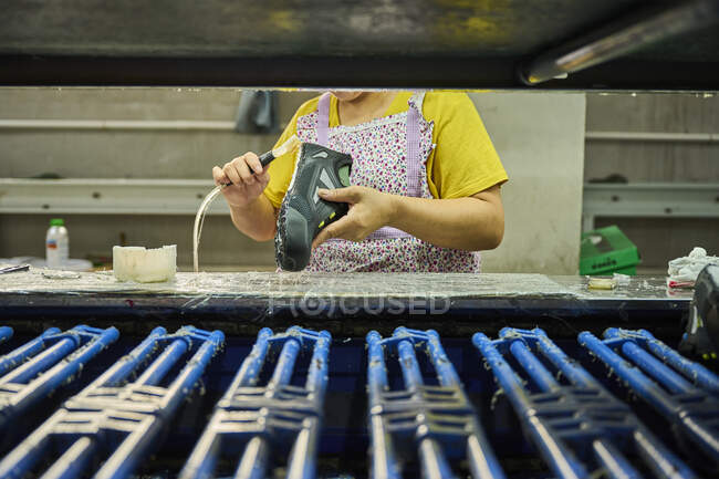 Деталь працівника, який застосовує клей до взуття, на виробничій лінії китайської фабрики взуття. — стокове фото