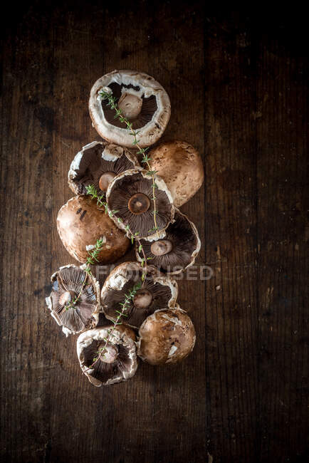 Top view of fresh raw champignons and sprigs of herbs placed on rustic wooden table — Stock Photo