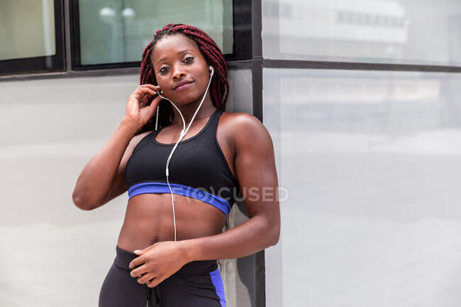 Muscular ethnic woman listening music — Stock Photo