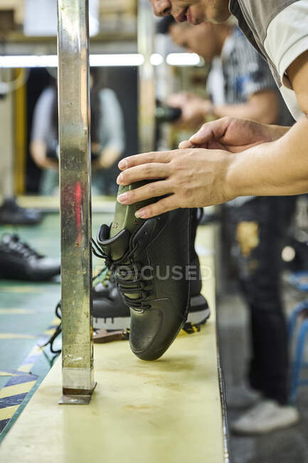 Деталь рук человека при проверке обуви в линии контроля качества на китайской обувной фабрике — стоковое фото
