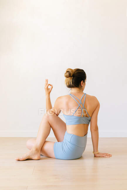 Femme méconnaissable en vêtements de sport assis dans Ardha Matsyendrasana et étirement du corps tout en faisant du yoga à la maison — Photo de stock