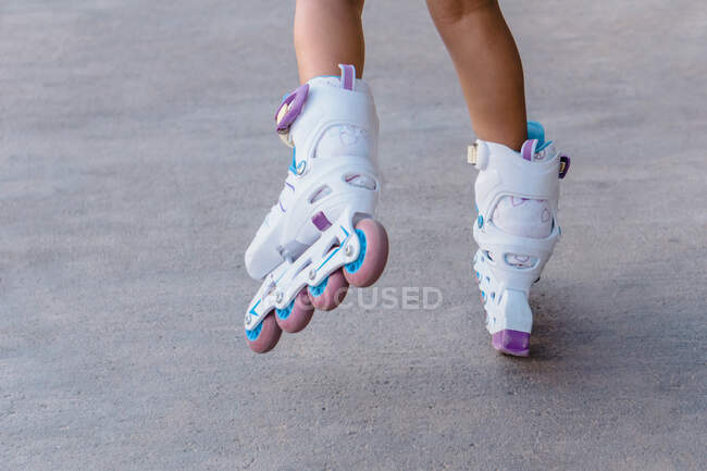 Back view of crop unrecognizable child roller skating on walkway on weekend in daytime — Stock Photo