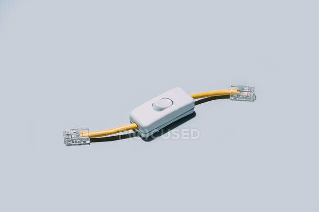 Conceptual shot of network cable with switch button isolated on grey background — Stock Photo