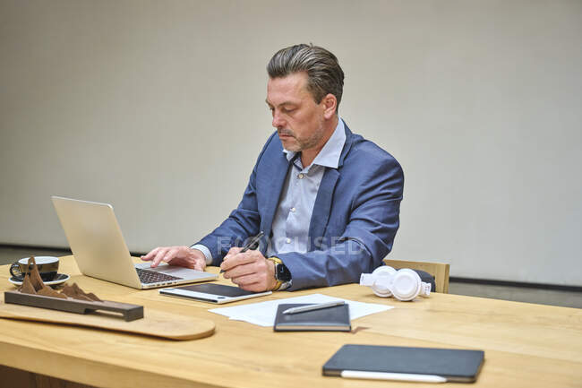 Designer am Schreibtisch, der mit seinem Tablet am Computer arbeitet — Stockfoto