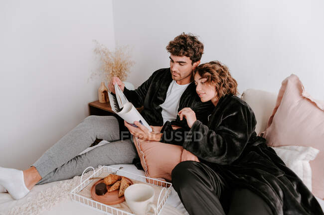 High angle of gentle couple relaxing on bed together while having breakfast in morning — Stock Photo