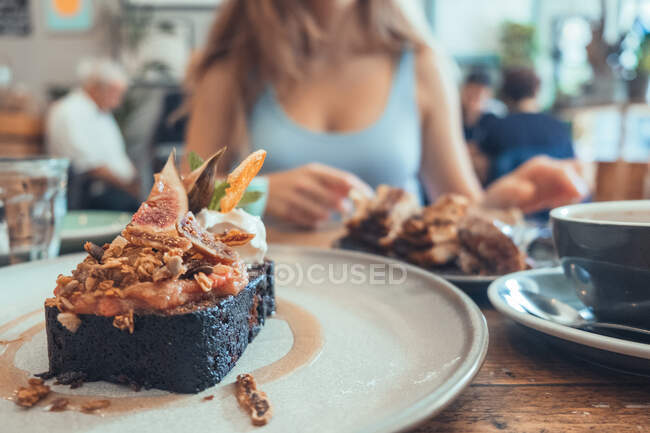 Sweet chocolate brownie with figs and whipped cream served on plate on table in cafe — Stock Photo