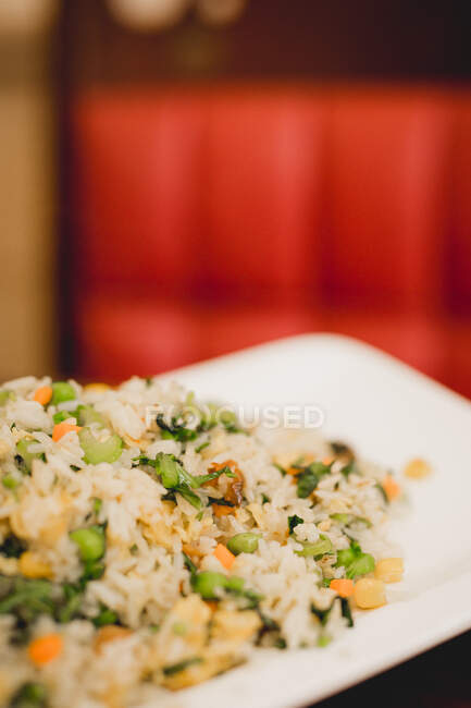 Verdure fritte piatto di riso asiatico contro sfondo rosso sfocato — Foto stock