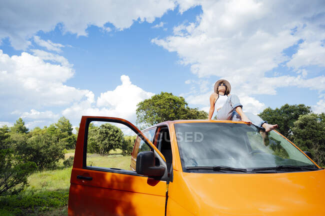 Sereno explorador do sexo feminino sentado no telhado da van e desfrutar de aventura de verão no dia ensolarado — Fotografia de Stock
