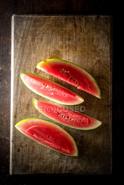 Angle élevé de tranches de pastèque sucrée mûre placées sur une table en bois sur fond sombre — Photo de stock
