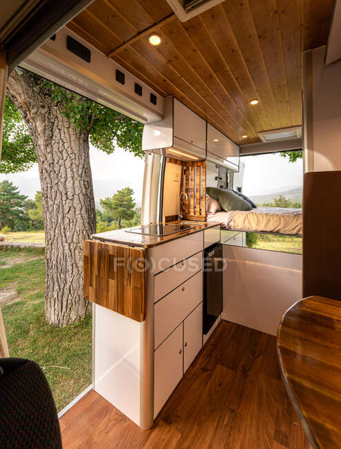 Modern interior of kitchen and bedroom in van parked on meadow in nature — Stock Photo