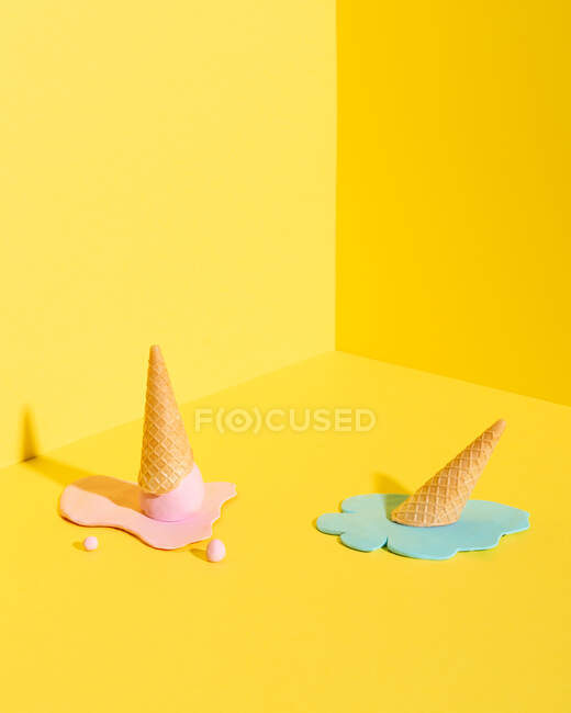 Макет синього, жовтого та рожевого морозива у вафельному конусі, розміщеному на жовтому тлі, що представляє літню концепцію — стокове фото