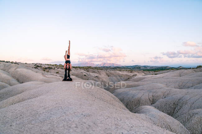 Vue latérale de la femme gracieuse équilibrage sur les jambes de l'homme pendant la séance d'acroyoga dans les montagnes — Photo de stock