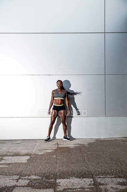 Позитивная афроамериканка в спортивной одежде смотрит в камеру, стоя на лестнице во время тренировки на открытом воздухе. — стоковое фото