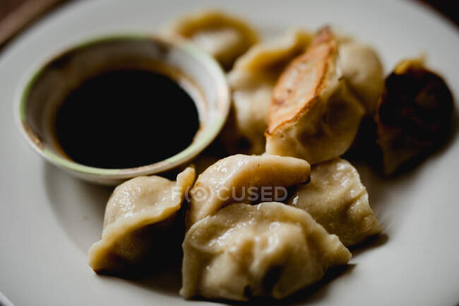 From above composition of steamed and roasted dumplings on white ceramic plate with soy sauce and chopsticks — Stock Photo