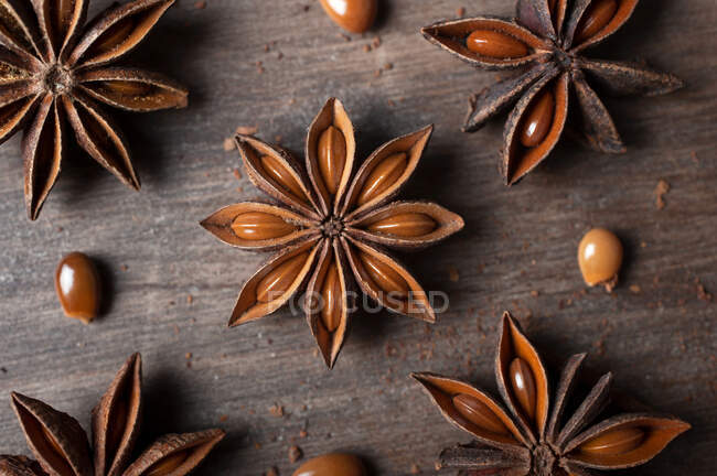 Gros plan d'étoiles d'anis séchées aromatiques avec des graines éparpillées sur une table en bois rustique pour la gastronomie concept fond — Photo de stock