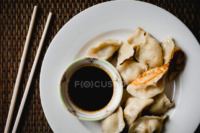 From above composition of steamed and roasted dumplings on white ceramic plate with soy sauce and chopsticks — Stock Photo