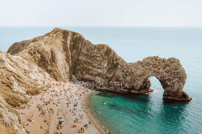 De cima paisagem marinha idílica com rochas chamadas Durdle Door e pessoas relaxando na praia no dia de verão — Fotografia de Stock