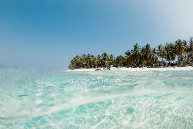 Magnífica vista al mar con agua transparente y playa de arena con palmeras en un día soleado - foto de stock