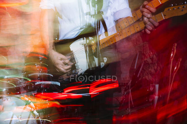 Escena borrosa del guitarrista tocando una guitarra eléctrica con escenario - foto de stock