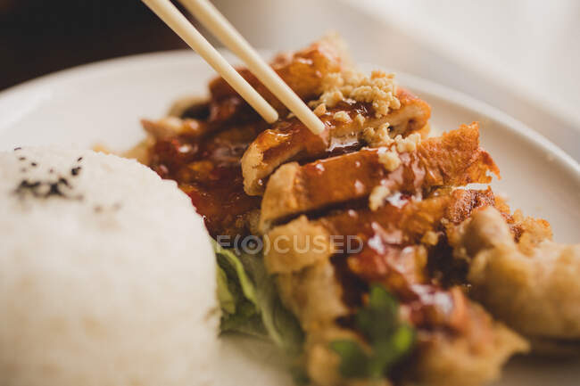 Woman sitting in Asian cafe and eating hot appetizing spicy duck with rice — Stock Photo