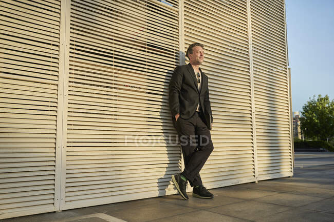 Бизнесмен встал перед офисным зданием на закате — стоковое фото