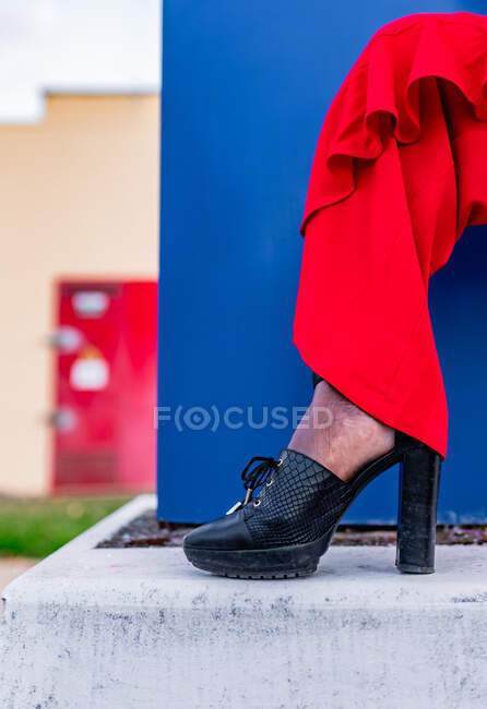 Crop unrecognizable ethnic female in trendy red apparel with ruffles and high heeled shoe in daytime — Stock Photo